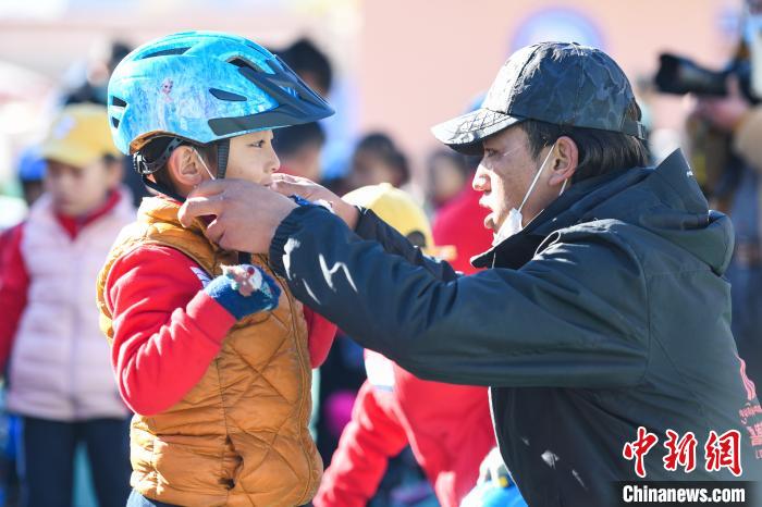 圖為拉薩市實(shí)驗(yàn)幼兒園孩子在教練的幫助下穿戴頭盔。　何蓬磊 攝