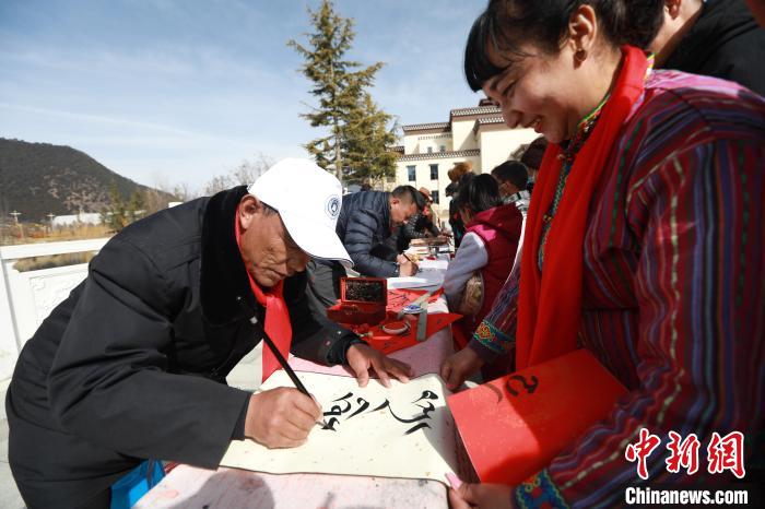 圖為林芝市文聯(lián)書法家協(xié)會(huì)會(huì)員向民眾贈(zèng)送藏文書法作品。　張力 攝