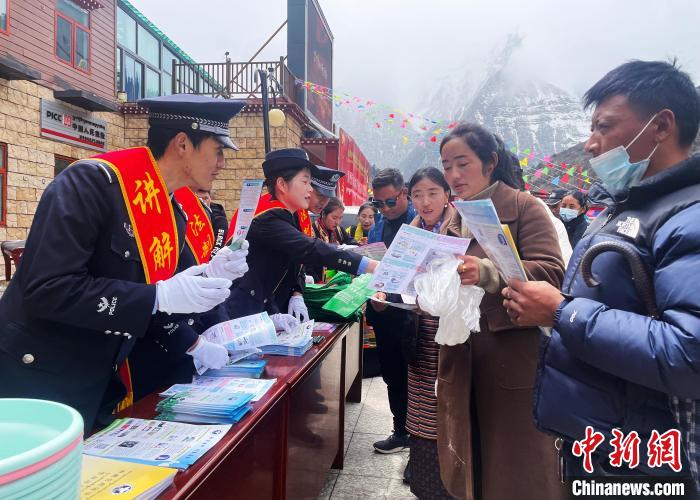 圖為山南玉麥邊境派出所民警為轄區(qū)群眾發(fā)放法律知識宣傳單。　鐘鑫 　攝